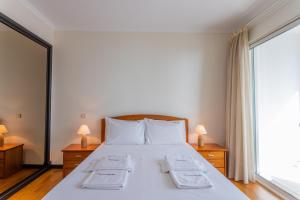 FLH Funchal Balcony Apartment with Sea View في فونشال: غرفة نوم مع سرير وملاءات بيضاء ونافذة كبيرة
