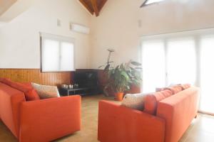 a living room with orange chairs and a flat screen tv at Mortazel River Houses in Montazel