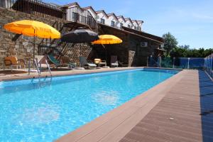 a swimming pool with two umbrellas and chairs at Mortazel River Houses in Montazel