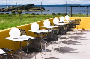 une rangée de tables et de chaises assises sur un balcon dans l'établissement Hotell Jeløy Radio, à Moss