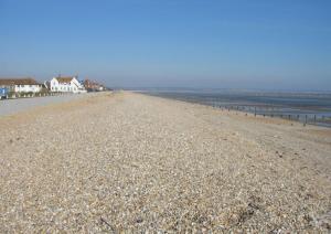 a sandy beach with houses and the ocean at Beautiful Spacious Holiday Home - Romney Sands in New Romney