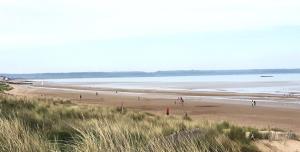 a group of people on a beach near the water at Beautiful Spacious Holiday Home - Romney Sands in New Romney
