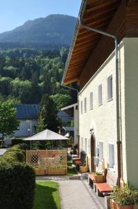 un edificio con patio con panchine e ombrellone di Ferienwohnung Haus Datz in Berchtesgaden a Berchtesgaden