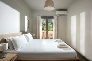 a bedroom with a large white bed and a window at Caravel Apartments Stalis in Stalida