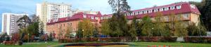 un gran edificio rojo con un parque delante de él en Record Hotel, en Zelenograd