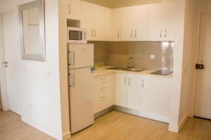 uma cozinha com armários brancos e um frigorífico branco em Apartamento Astro em Quarteira
