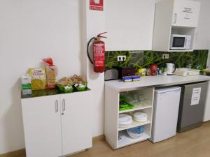 una pequeña cocina con armarios blancos y microondas en Grelo Hostel, en Ourense