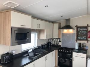 a kitchen with white cabinets and a black counter top at Beautiful Spacious Holiday Home - Romney Sands in New Romney