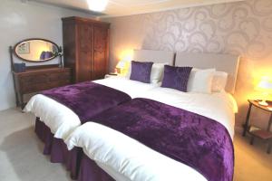 a bedroom with a large bed with purple sheets at Mellowvean in St. Agnes