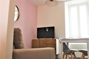 sala de estar con paredes de color rosa, silla y TV en Cocooning Studio, en Pontivy