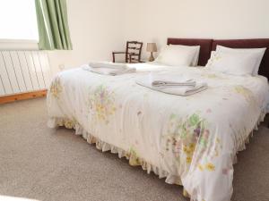 a bed with a white blanket with flowers on it at Zoey Cottage in Skipton