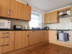 eine Küche mit Holzschränken und einer Mikrowelle in der Unterkunft Katy's Cottage in Skipton + 21 Fotos