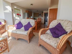 uma sala de estar com 2 cadeiras e almofadas roxas em Katy's Cottage em Skipton