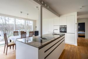 a kitchen with white cabinets and a dining room at Ferienhaus direkt am See - Kamin, Klima, Sauna und Boot in Friedland