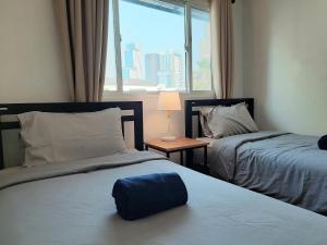 a bedroom with two beds and a window with a view at Pingplalee Female House in Bangkok