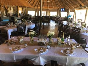 un comedor con mesas y sillas blancas en Suricata Retreat, en Mathathane