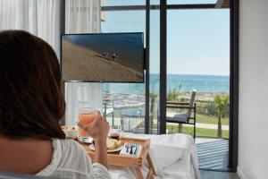 una mujer sentada en una mesa con un vaso de jugo en La Mer Resort & Spa - Adults Only en Georgioupolis