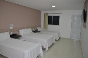 um quarto de hotel com duas camas e uma janela em Hotel La Ville em Sousa