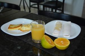 una tavola con due piatti di cibo e un bicchiere di succo d'arancia di Hotel La Ville a Sousa