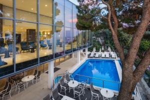 Vistas a un edificio con piscina, mesas y sillas en Royal Ariston Hotel, en Dubrovnik