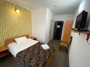 リヴィウにあるAutopark Hotelのベッド1台、薄型テレビが備わるホテルルームです。