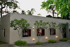 a white house with trees in front of it at The Aluthgama House in Aluthgama