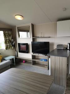 a living room with a flat screen tv and a kitchen at lakeland leisure park in Flookburgh