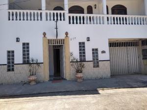 a white building with two potted plants in front of it at Sonhos de sereia in Ponta da Fruta