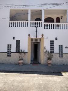 a white building with two potted plants in front of it at Sonhos de sereia in Ponta da Fruta