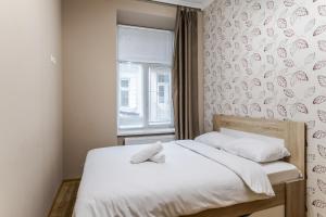 1 dormitorio con 1 cama con sábanas blancas y ventana en Apartment on Stavropihiiska Street 1, en Leópolis