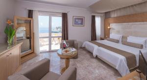 ein Hotelzimmer mit einem großen Bett und einem Balkon in der Unterkunft Athina Palace Resort & Spa in Agia Pelagia