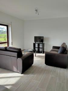 a living room with two leather couches and a television at Residencias Ana Carmen in Viana do Castelo