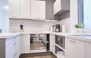 una cocina blanca con armarios y electrodomésticos blancos en Falkenapartment Berlin, en Berlín