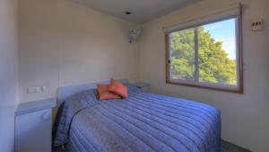 a bedroom with a bed with a blue comforter and a window at Airport Tourist Village Melbourne in Melbourne