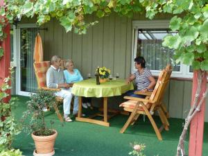 Un grupo de personas sentadas alrededor de una mesa en un patio. en Pension Irene Nist, en Bad Birnbach
