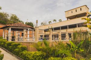 un gran edificio amarillo con porche y un edificio en Hotel Manantial, en Buga