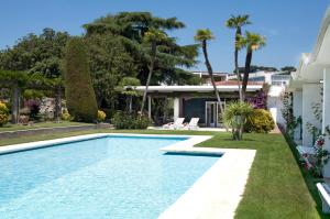una piscina en el patio trasero de una casa con palmeras en BarcelonaVacances-La Mansión, en Sant Pol de Mar
