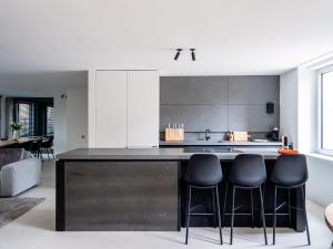 eine Küche mit einer schwarzen Theke und schwarzen Hockern in der Unterkunft Maison N in Gent