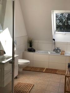 a bathroom with a tub and a toilet and a window at Apartment Hoyerhagen in Hoyerhagen