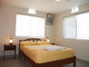 a bedroom with a bed with yellow sheets and two windows at Apartamento de Lujo en Tonsupa in Tonsupa
