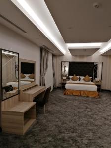 a hotel room with two beds and a desk at Al Maali Hotel Jazan in Jazan