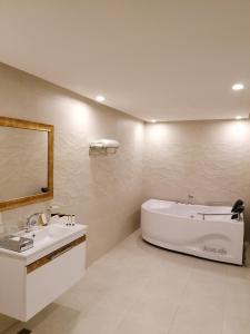 La salle de bains est pourvue d'une baignoire, d'un lavabo et d'un miroir. dans l'établissement Al Maali Hotel Jazan, à Jazan