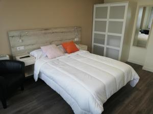 a bedroom with a large white bed with two pillows at Pensión La Intermodal in Santiago de Compostela +40 photos