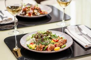 two plates of food on a table with glasses of wine at Deluxe Hotel Kupava in Lviv +49 photos