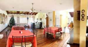 a dining room with red tables and chairs and a christmas tree at Hosteria San Carlos Tababela in Tababela