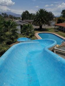 uma grande piscina azul com palmeiras ao fundo em Hosteria San Carlos Tababela em Tababela
