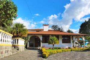 a house with palm trees in front of it at Hosteria San Carlos Tababela in Tababela