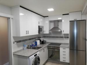 a kitchen with white cabinets and a stainless steel refrigerator at Pensión La Intermodal in Santiago de Compostela