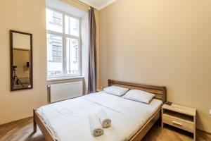 1 dormitorio con 1 cama con sábanas blancas y ventana en Apartment on Stavropihiiska Street 3, en Leópolis