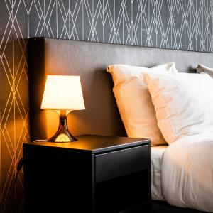 Una cama con mesita de noche con una lámpara. en Hotel Brasserie de Huifkar en Middelburg